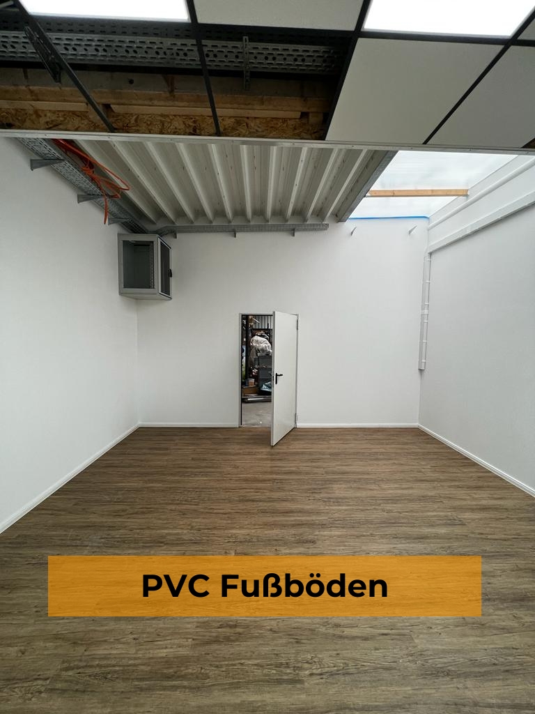 Neu verlegter PVC-Bodenbelag in brauner Holzoptik in einem frisch renovierten Raum mit weißen Wänden, geöffneter Tür, abgehängter Rasterdecke und einem orangefarbenen Banner mit der Aufschrift „PVC Fußböden“.