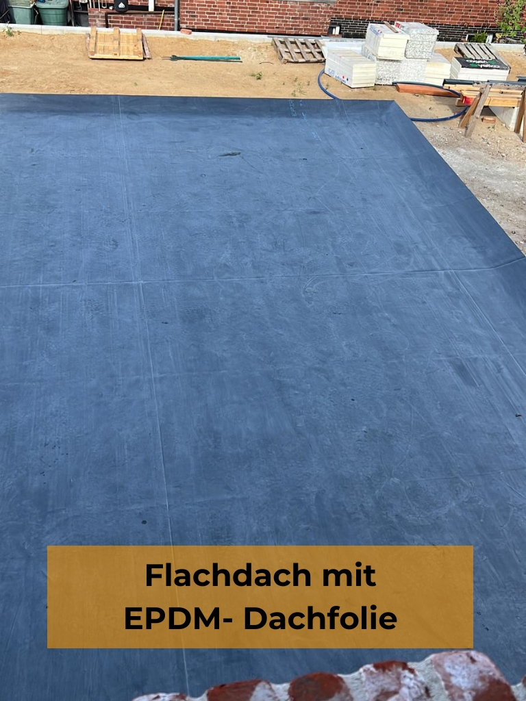 Flachdachabdichtung mit nahtloser, dunkelgrauer EPDM-Dachfolie auf einer Baustelle mit Sandboden und Baumaterialien im Hintergrund; unten ein orangefarbenes Textfeld mit der Aufschrift „Flachdach mit EPDM-Dachfolie“.